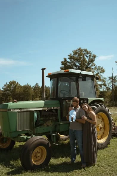 Ethan with his family beside a green tractor